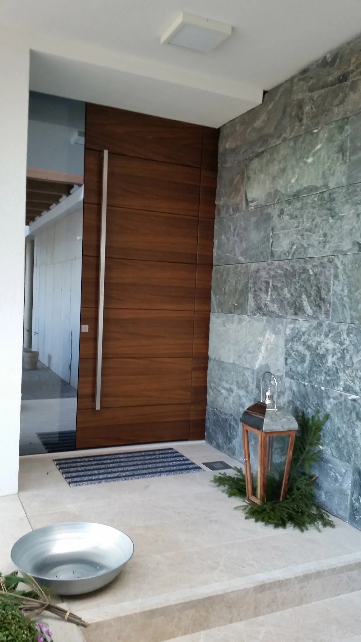 Hauseingang mit Holztür, Glaselement und Natursteinwand