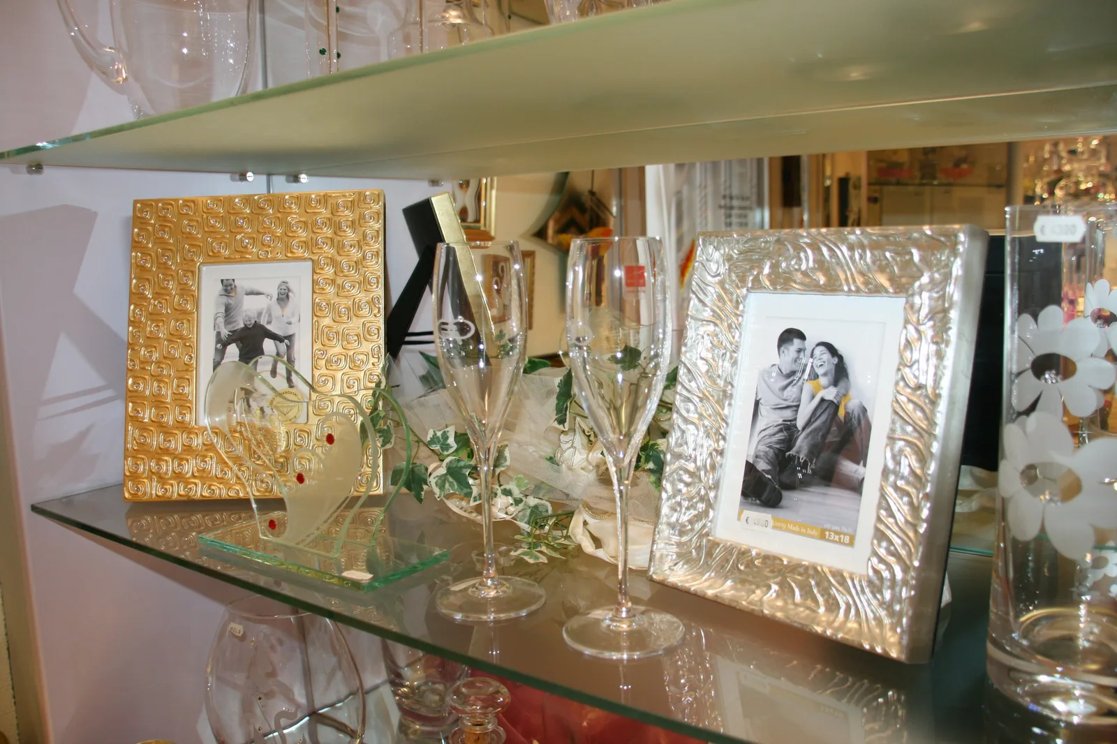 Bilderrahmen, Gläser und Dekoration aus Glas in einer beleuchteten Vitrine