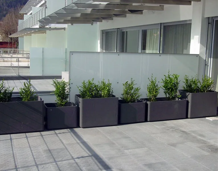 Glastrennwand im Außenbereich einer Terrasse mit Pflanztrögen