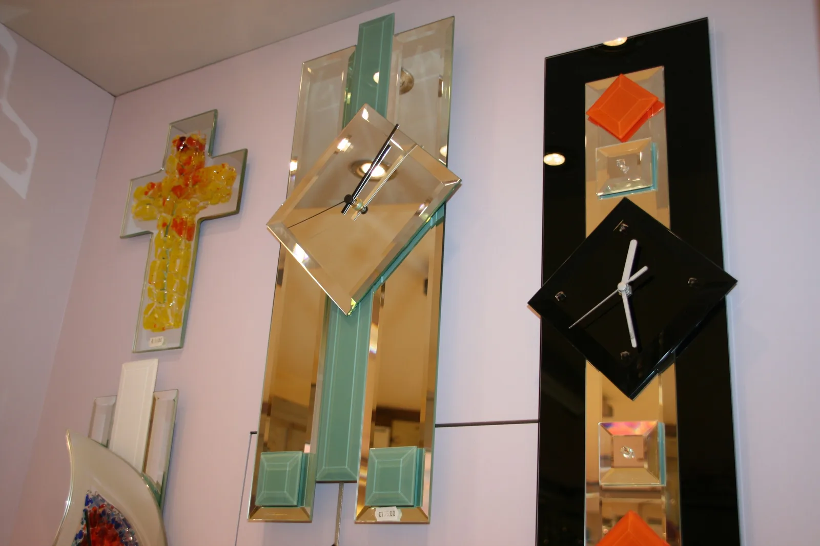 Wanduhren, Wandkreuze und Dekoration aus farbigem Glas an einer Wand
